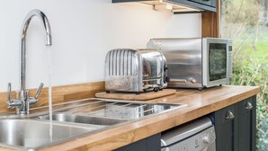 Eine Küche mit Spüle aus Edelstahl, einem Toaster und einer Mikrowelle auf einer Holz Arbeitsplatte.