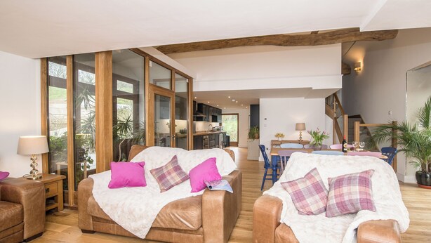 Ein geräumiges Wohnzimmer mit zwei Ledersofas, einem Esstisch und einer Küche im Hintergrund.