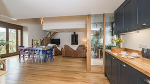 Eine geräumige Küche mit Holzboden, eine Essecke mit blauen Stühlen und eine Treppe, die zu einer oberen Ebene führt.