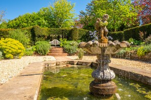 Un jardin avec une fontaine, un banc en bois et un escalier en pierre.