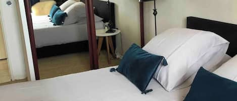 A hotel room with a bed, two bedside lamps, a small table, and a picture on the wall.