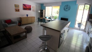 Una cocina moderna con una isla central, un comedor con sillas y una sala de estar con un sofá y una mesa de centro.