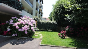 Un edificio residencial con un jardín cuidado, con hortensias rosadas y un camino de piedra.
