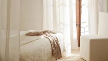 Une chambre à coucher avec un lit, une chaise et une fenêtre avec des rideaux.