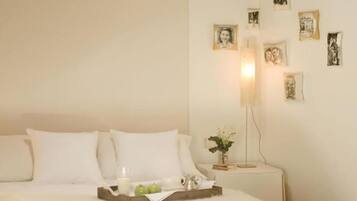 A neatly made bed with a white bedspread, a bedside table with a lamp, and several framed pictures on the wall.