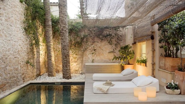 A serene outdoor relaxation area with a pool, lounge chairs, and ambient lighting. - S'Hotelet de Santanyi (Santanyi)