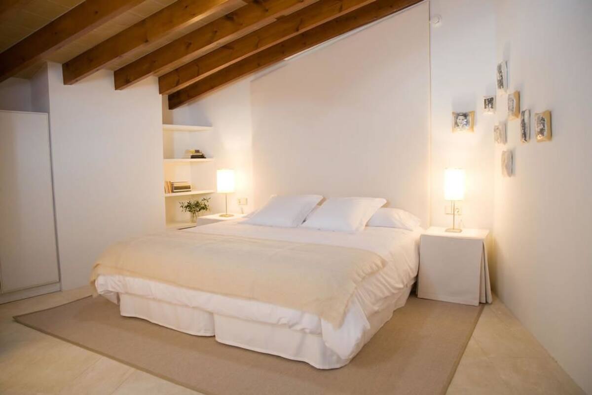 Une chambre à coucher avec un grand lit, des tables de chevet et des étagères murales.
