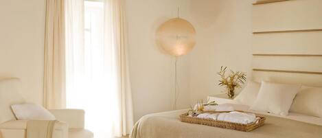 Une chambre à coucher avec un lit, une table de chevet, une lampe et une fenêtre avec des rideaux.