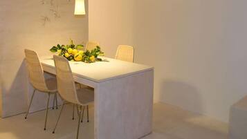 Uma área de refeições com uma mesa posta para quatro pessoas, rodeada por cadeiras.