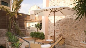 An outdoor seating area with a table, chairs, and an umbrella. - S'Hotelet de Santanyi (Santanyi)