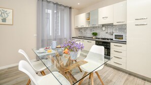 A modern kitchen with white cabinets, a glass dining table, and a potted plant. - 50 meters from the lake, in the historic center with a terrace. Stella House (Desenzano del Garda)