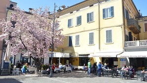 A public square with outdoor seating, a yellow building with multiple windows, and a cherry blossom tree. - 50 meters from the lake, in the historic center with a terrace. Stella House (Desenzano del Garda)