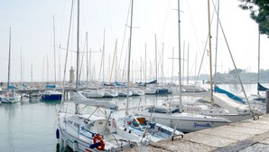 A marina with multiple boats docked, a lighthouse in the background, and a stone quay. - 50 meters from the lake, in the historic center with a terrace. Stella House (Desenzano del Garda)