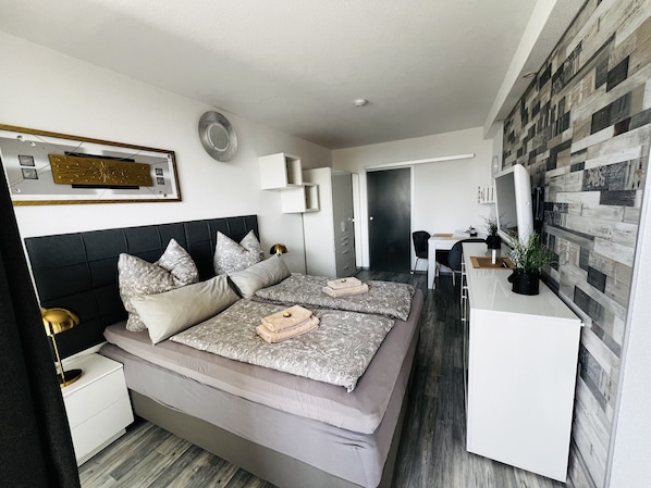 Une chambre moderne avec un grand lit, des tables de chevet, un bureau et une armoire.