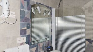 A bathroom with a large mirror, a hairdryer, a shower, and a towel rack. - VISTA VELETA CASA ROMERO (Capileira)