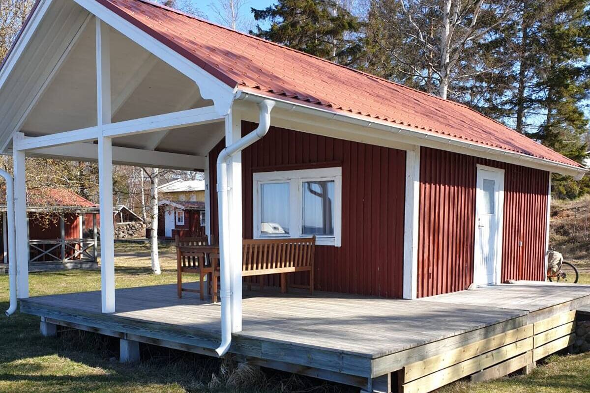 A red wooden cabin with a white porch and a small window.