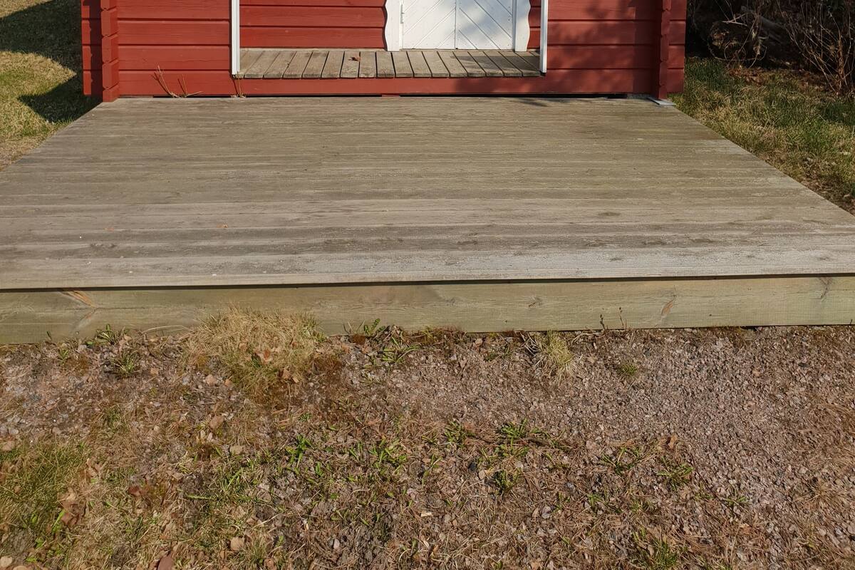 A small, single-story red cabin with a white door and window, a number '17' on the door, and a wooden deck in front.