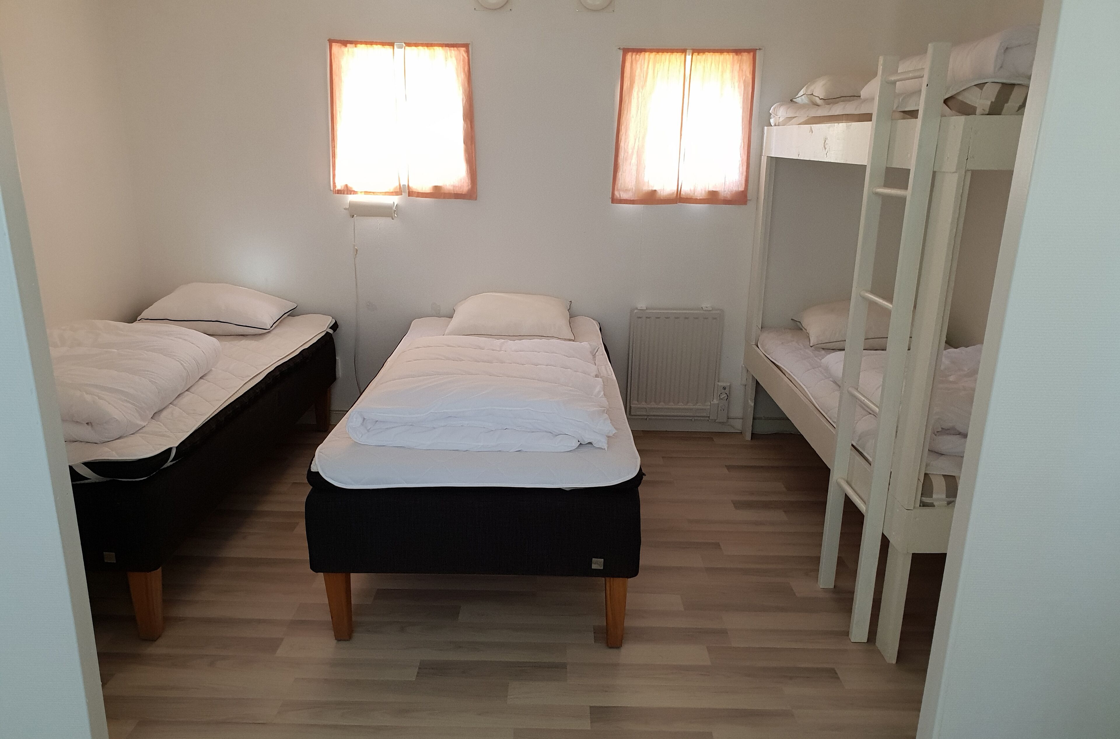 A room with two single beds, a bunk bed, and a desk.