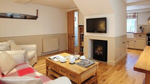 A living room with a fireplace, a television, and a dining area. - 1 bedroom accommodation in Tunbridge Wells (Tunbridge Wells)