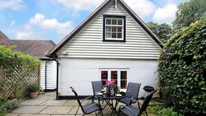 A white house with a black window and a small porch with a table and chairs. - 1 bedroom accommodation in Tunbridge Wells (Tunbridge Wells)