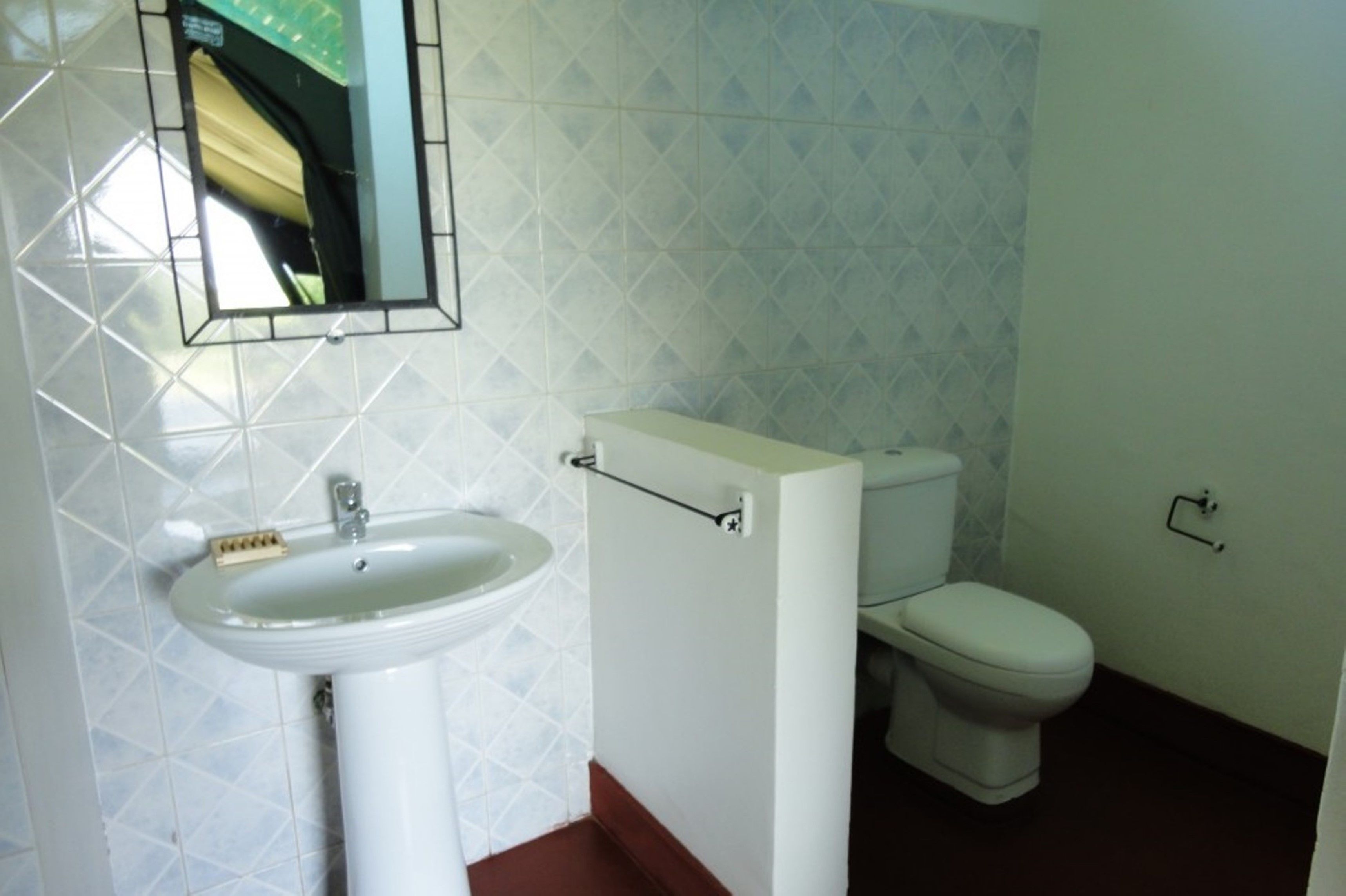 Un baño con lavamanos, inodoro y espejo en la pared.