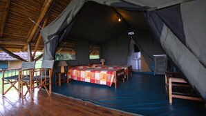 A tented accommodation with a bed, chairs, and a small table. - Bwana Tembo Safari Lodge (Pakwach)
