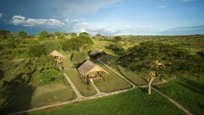An aerial view of a rural property with two wooden structures, surrounded by lush greenery and a clear sky. - Bwana Tembo Safari Lodge (Pakwach)