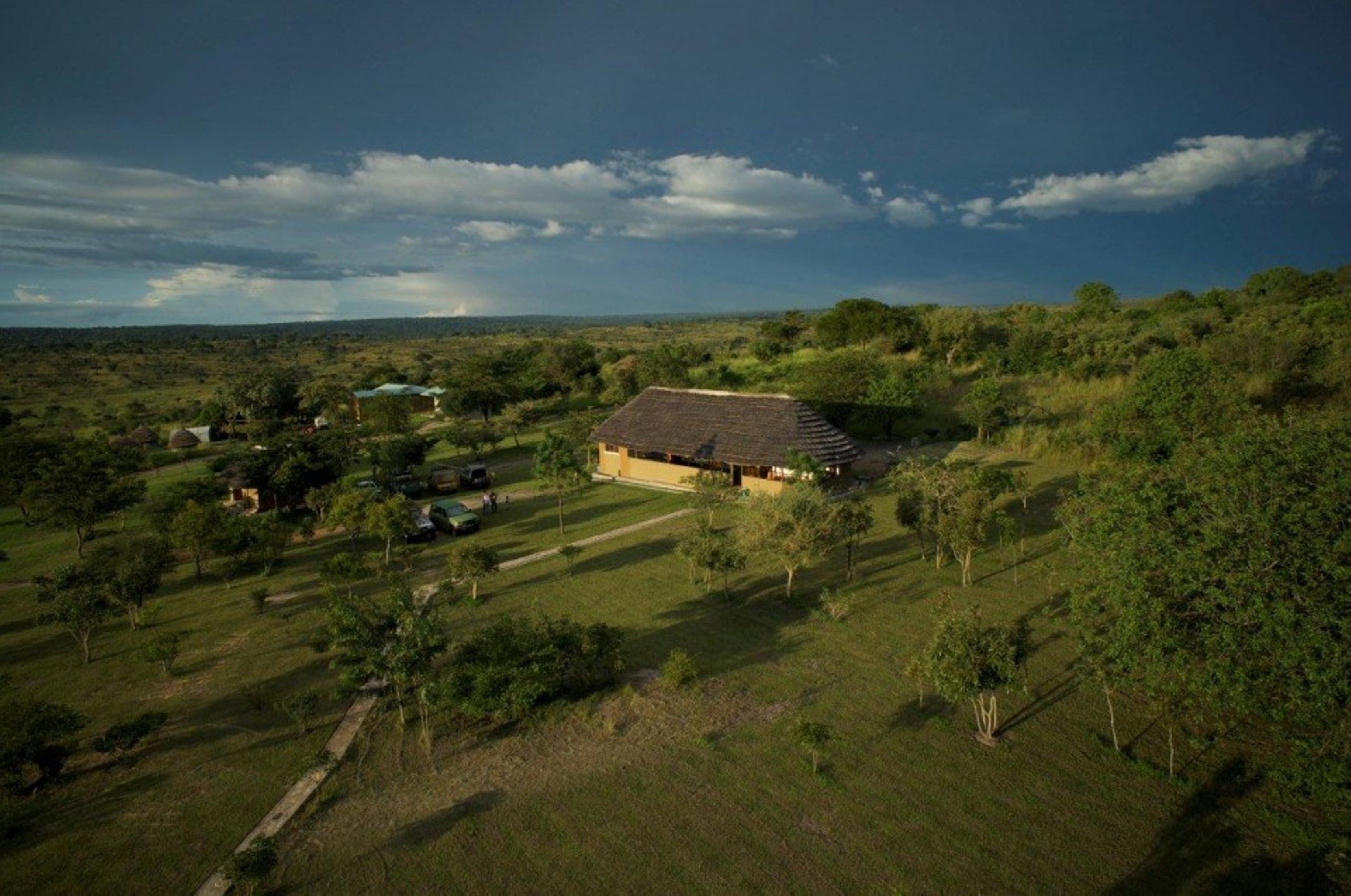 A rural landscape with a large house surrounded by trees and open fields.