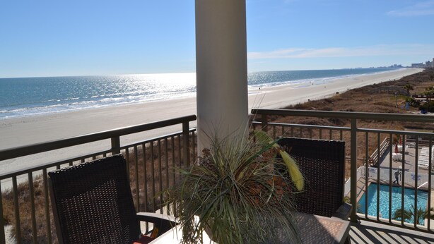 Een balkon met uitzicht op het strand en het zwembad.
