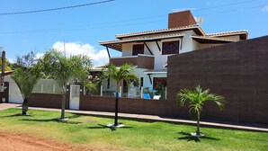 A residential area with a modern house, a paved driveway, and a well-maintained lawn. - Beach House in Guarajuba, North Coast of Bahia (Camaçari)