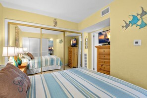 A bedroom with a bed, a dresser, a television, and a mirror.