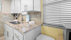 Cucina con piani di lavoro in granito, elettrodomestici in acciaio inossidabile e mobili bianchi.