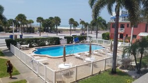 Una piscina con recinzione bianca, lettini e ombrelloni.