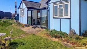 Une maison avec une entrée dotée d’une porte en verre, un petit patio et un jardin fleuri.