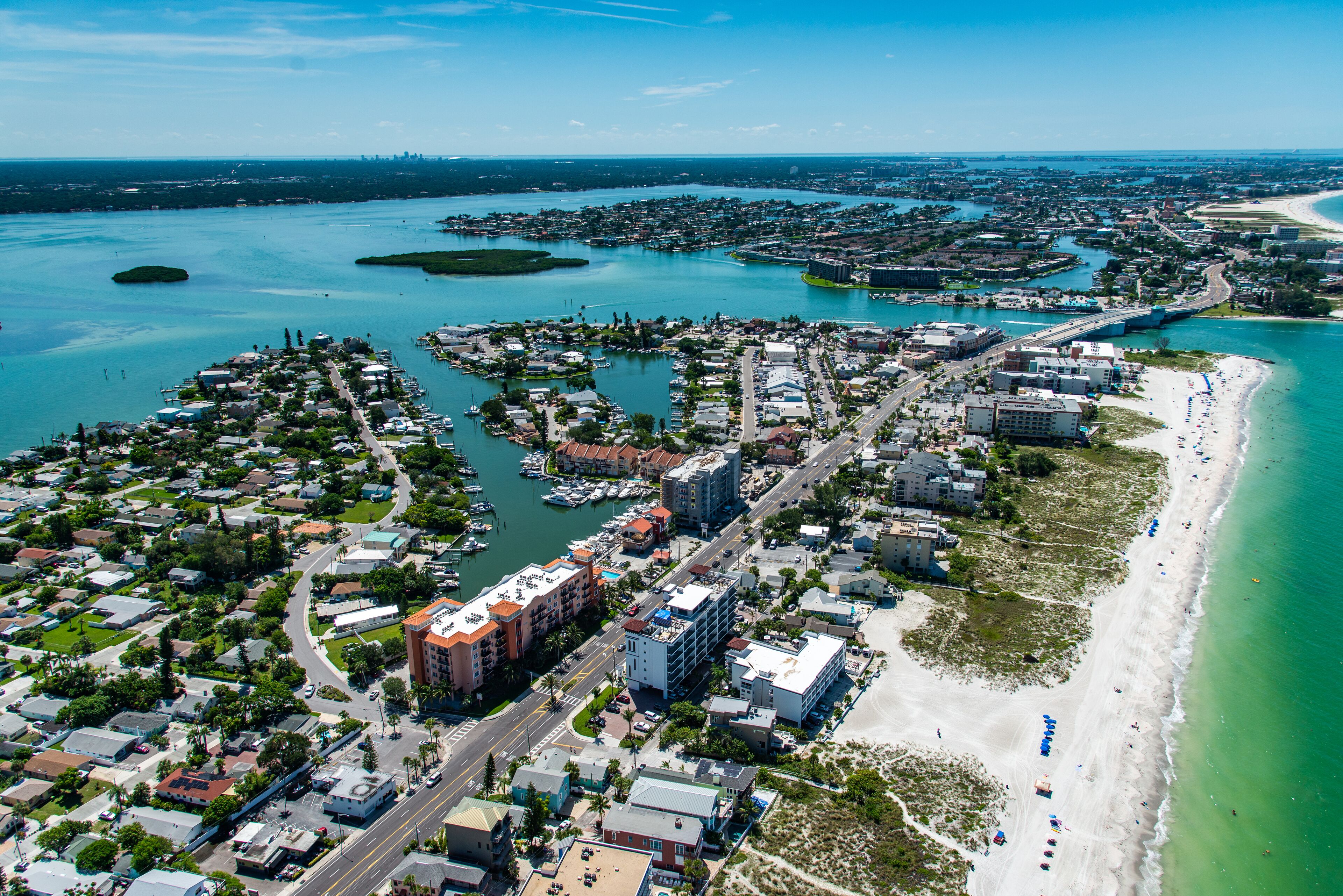 An aerial view of a coastal city with a marina, beachfront, and dense residential areas.