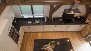 Una cocina moderna con una isla central, vigas de madera y vistas al exterior a través del ventanal.