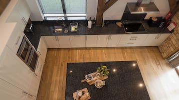 Een moderne keuken met een centraal eiland, houten balken en uitzicht op de omgeving door het raam.