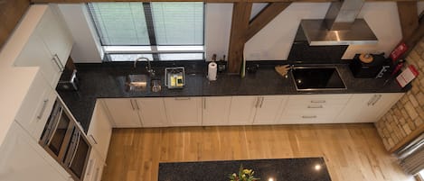 Una cocina moderna con una isla central, vigas de madera y vistas al exterior a través del ventanal.