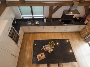 Una cocina moderna con una isla central, vigas de madera y vistas al exterior a través del ventanal.