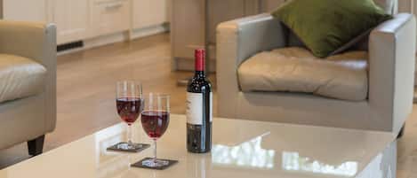 A modern kitchen with a dining area featuring a white table with two wine glasses and a bottle.
