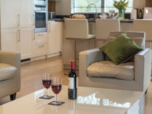 A modern kitchen with a dining area featuring a white table with two wine glasses and a bottle.