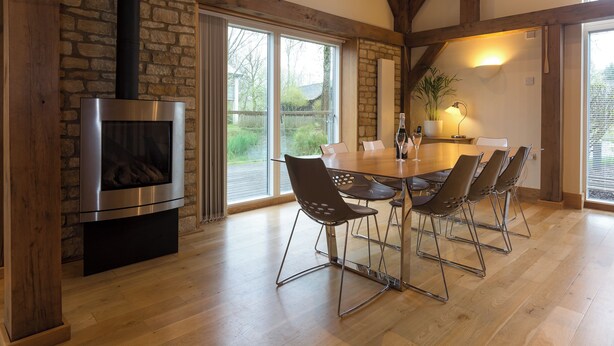 Un comedor con pared de piedra, chimenea y ventana grande.