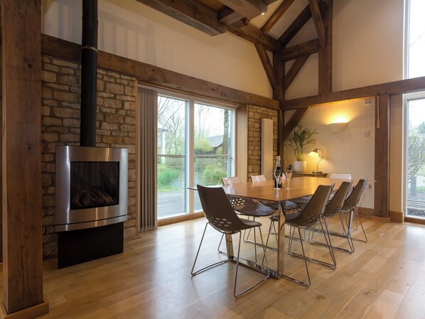 Un comedor con pared de piedra, chimenea y ventana grande.