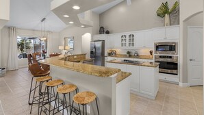 Eine moderne Küche mit einer zentralen Kochinsel, Barhocker und Edelstahlgeräten.