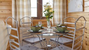 A dining area with a round glass table, metal chairs, and a vase of flowers. - 2 bedroom accommodation in Churchstanton, near Honiton (Churchstanton, near Honiton)