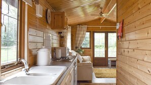 A wooden cabin with a kitchen area, a dining table, and a sofa. - 2 bedroom accommodation in Churchstanton, near Honiton (Churchstanton, near Honiton)