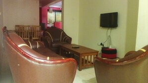 Un salón con sofás de cuero, una mesa de centro de madera y un televisor instalado en la pared.