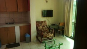 Un espacio habitable compacto con kitchenette, comedor y zona de estar con televisor.