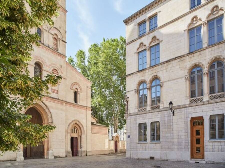 A courtyard with a building featuring arched windows and a door.