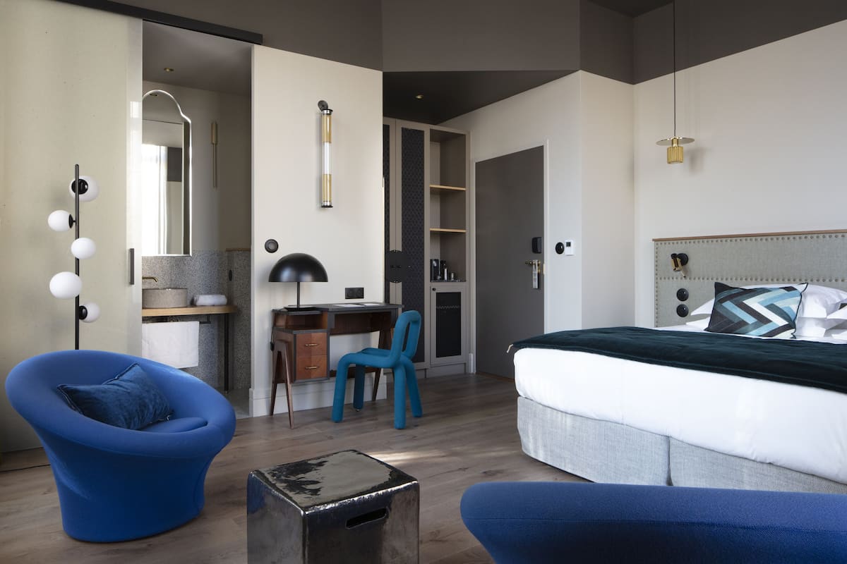 A modern bedroom with a bed, a desk, a chair, and a wardrobe.